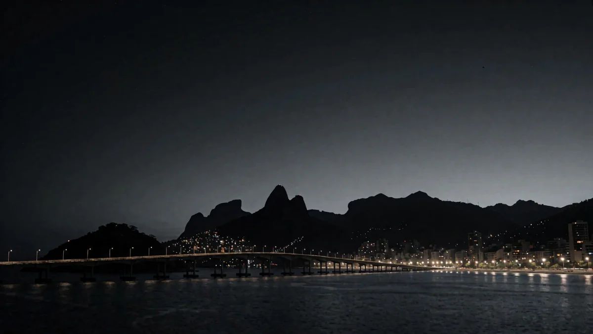 Un puente sobre una bahía con montañas en silueta y luces cálidas de la ciudad en hora azul