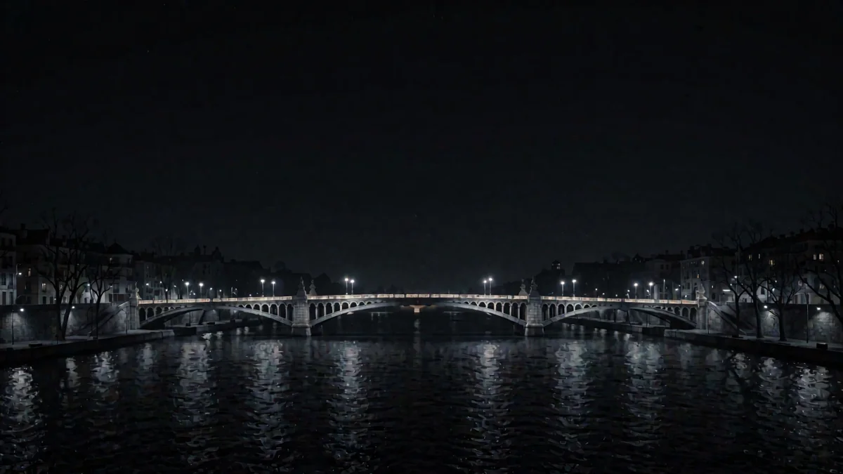 Una orla con un puente iluminado sobre un río y luces cálidas en hora azul