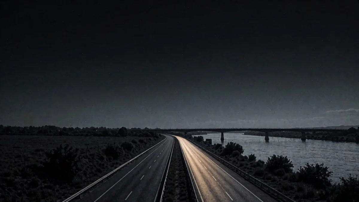 Una carretera recta del cerrado con un cielo enorme y un puente sobre un río ancho en hora azul