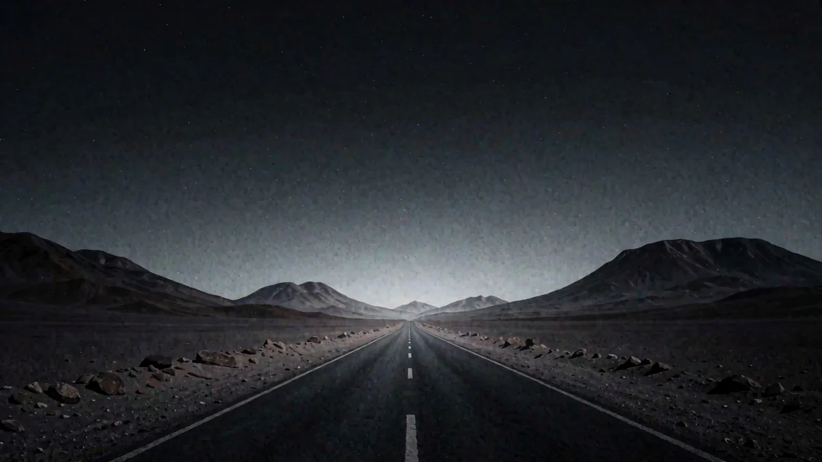 Una carretera recta del desierto de Atacama entre cerros ocres en hora azul con una luz cálida lejana