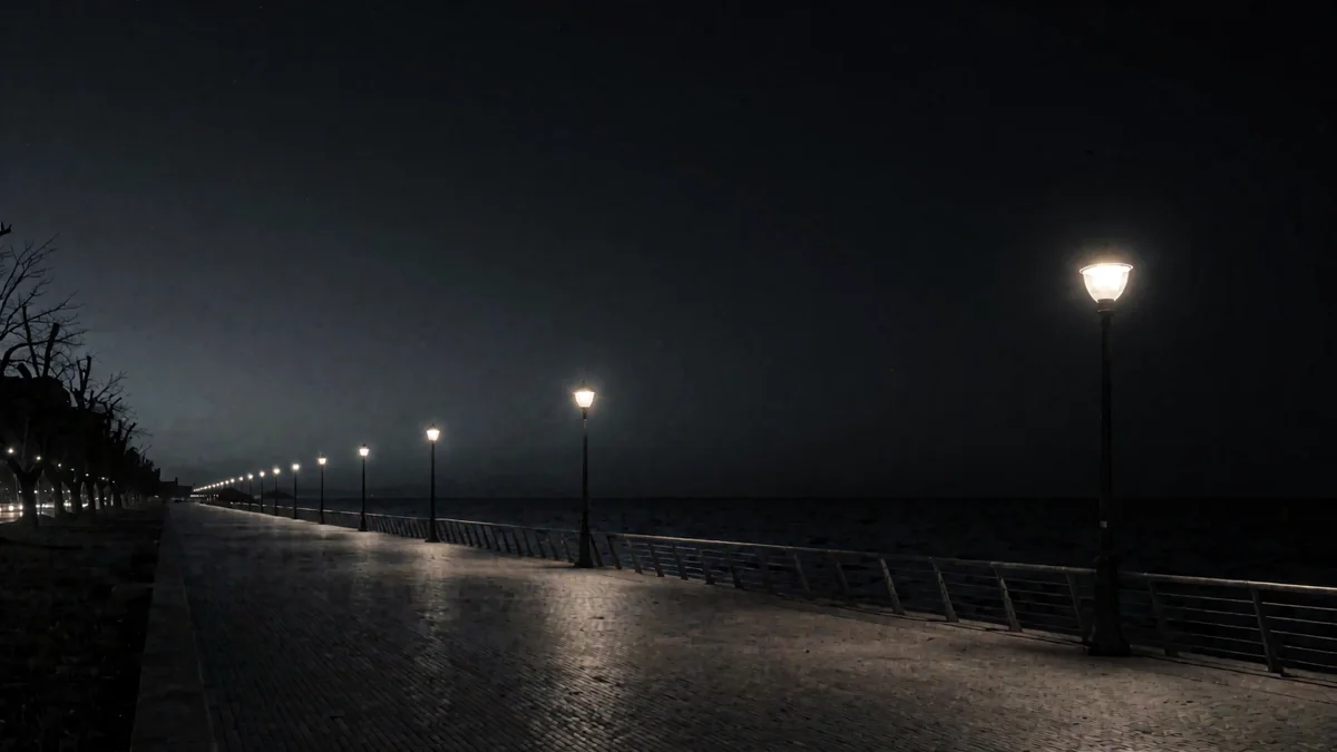La rambla de Montevideo vacía en hora azul con faroles cálidos y el río oscuro